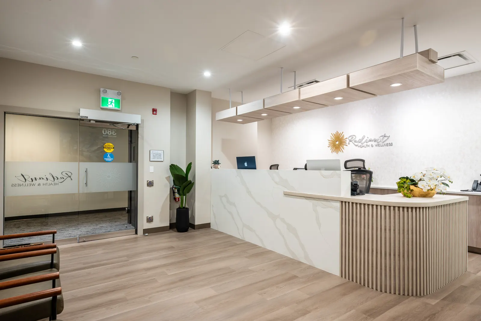Finished commercial tenant improvement in Calgary — a reception area build-out with a custom quartz reception desk, wood-slat paneling, and backlit signage.